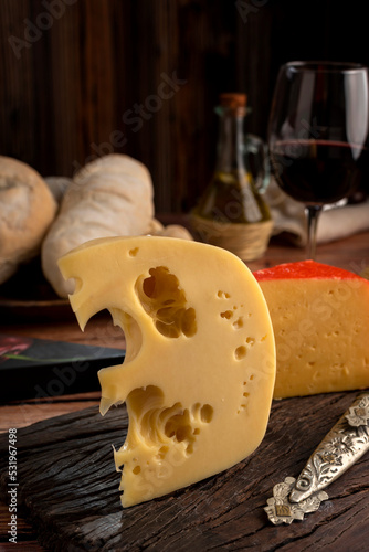 Varied cheese table, blue cheese Fontina Gruyer Cheese Teetilla in wooden table with red wine glass Pimentero oil and Round homemade fields of field and rustic knife photo