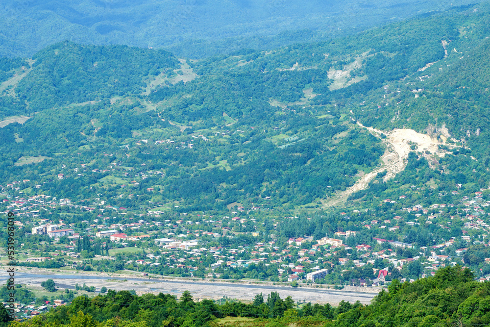 Georgian mountain landscape with a country road, a view of the village on the banks of a mountain river