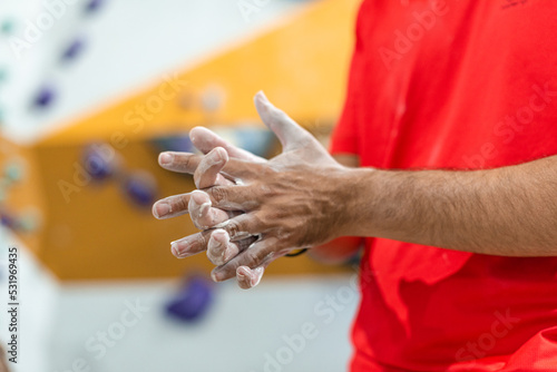 Man spreading liquid magnesium on his hands to practice climbing wall
