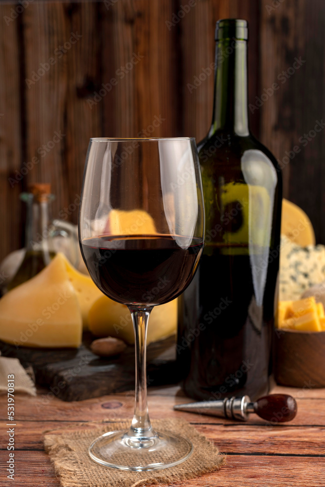 Red wine cup with varieties of oil and pepper background cheese and red wine bottle