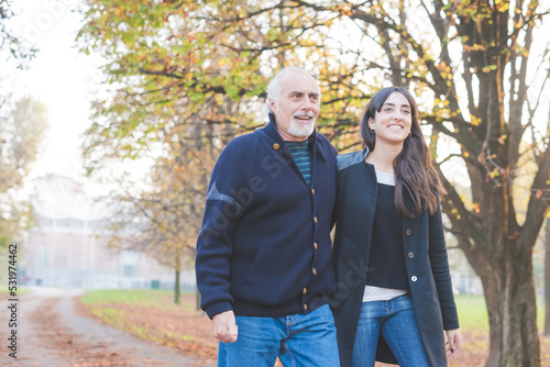 Adult father and daughter relaxing together walking arm in arm outdoors