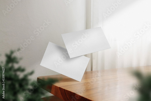 Clean minimal business card mockup floating on wiiden table with plant
