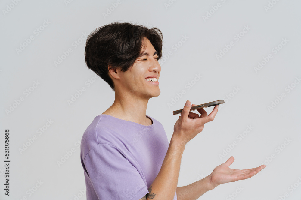 Young asian man wearing t-shirt gesturing and talking on cellphone Young asian man wearing t-shirt gesturing and talking on cellphone