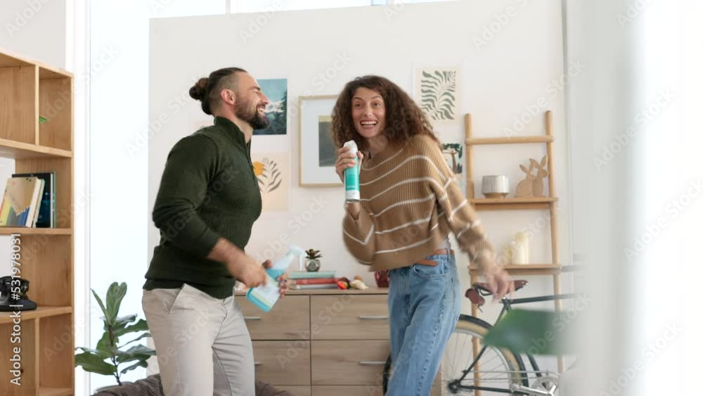 Singing couple, dance or cleaning house living room with spray bottle, housekeeping product or home cleaner. Happy smile, fun man or comic woman in spring clean bond for interior hygiene maintenance Singing couple, dance or cleaning house living room with spray bottle, housekeeping product or home cleaner. Happy smile, fun man or comic woman in spring clean bond for interior hygiene maintenance