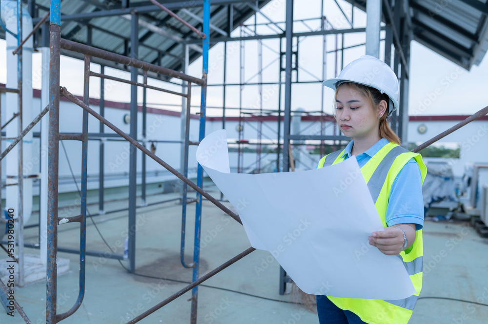 Young engineers working,Plan for construction of a warehouse,See the construction drawings for the storage facility. Young engineers working,Plan for construction of a warehouse,See the construction drawings for the storage facility.