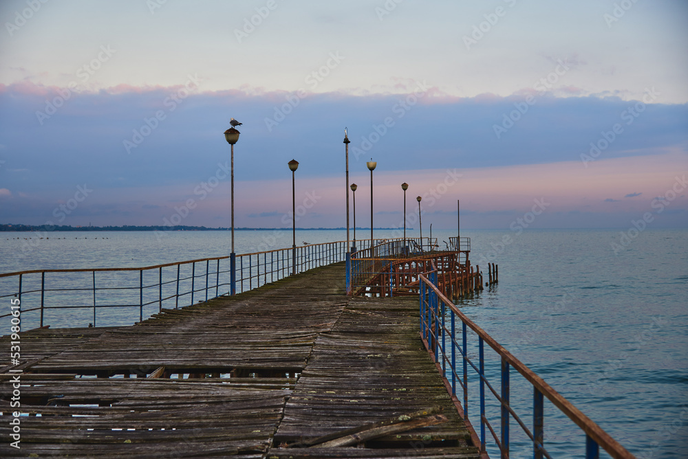 A pier stretching far out to sea against the sunset.