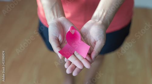 Woman hands holding pink cancer awareness ribbon, cancer awareness and abdominal cancer awareness