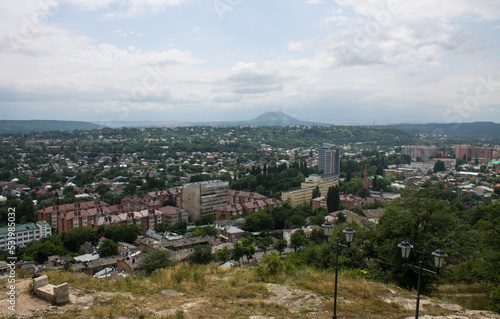 Panoramic top view of Pyatigorsk, Stavropol territory with residential buildings among green trees and cloudy sky above the horizon © Inna