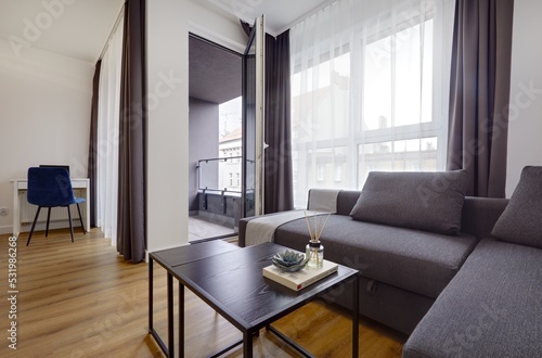 Jasny salon w apartamencie z szarą kanapą, stolikiem kawoym i telewiziorem © arteffect.pl