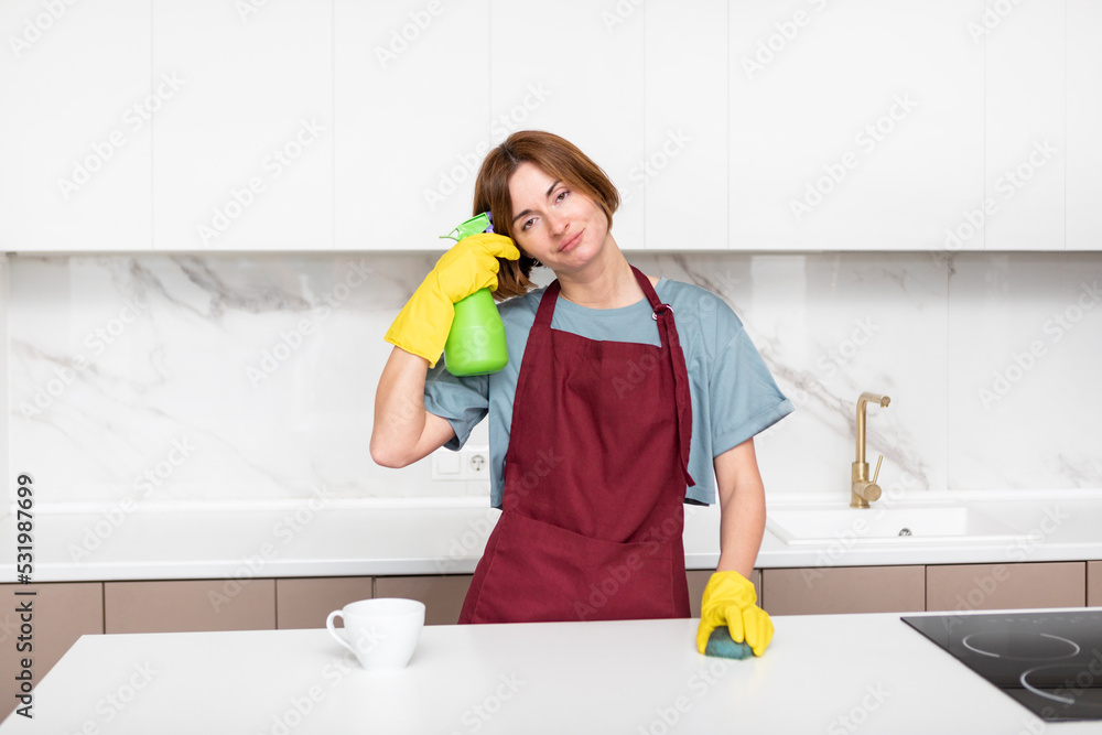 Tired woman standing in the kitchen after cleaning house Tired woman standing in the kitchen after cleaning house
