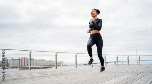 A woman runs, smiles, trains fitness in a tight-fitting tracksuit.