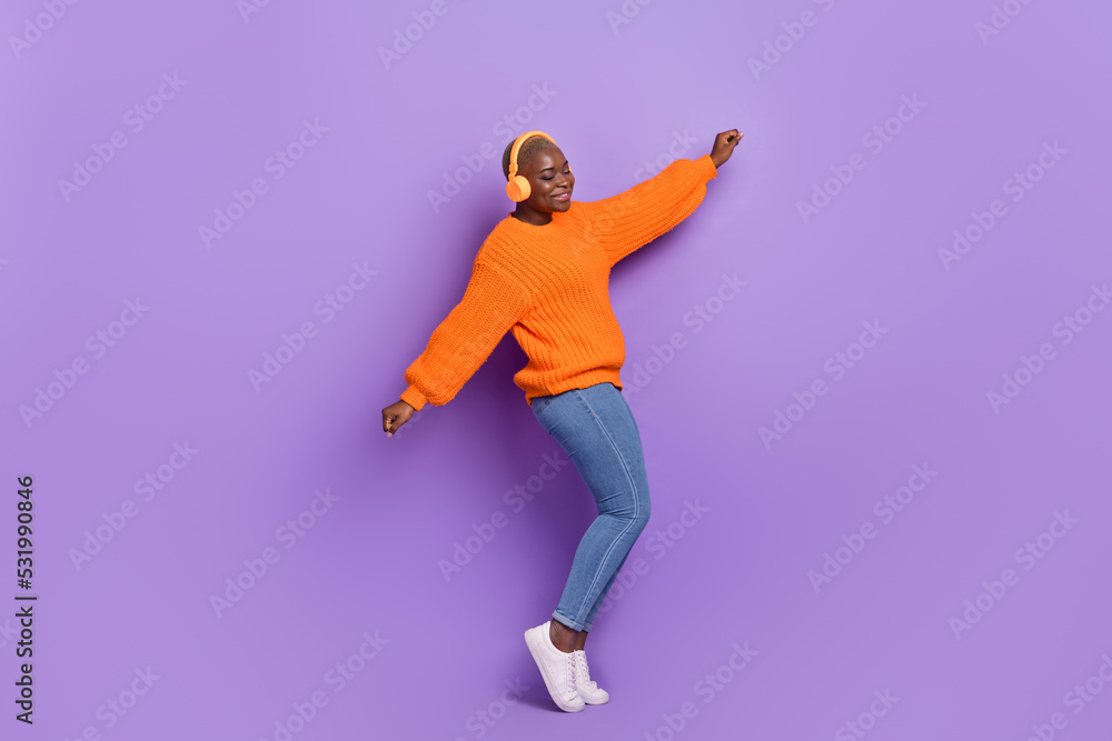 Full length photo of cute young girl listen music weekend dressed stylish autumn orange knitwear jumper isolated on violet color background