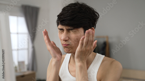 Canvas Print asian Japanese male is slapping his own face to cheer himself up and looking at his reflection in the mirror with a smile in the morning at his apartment