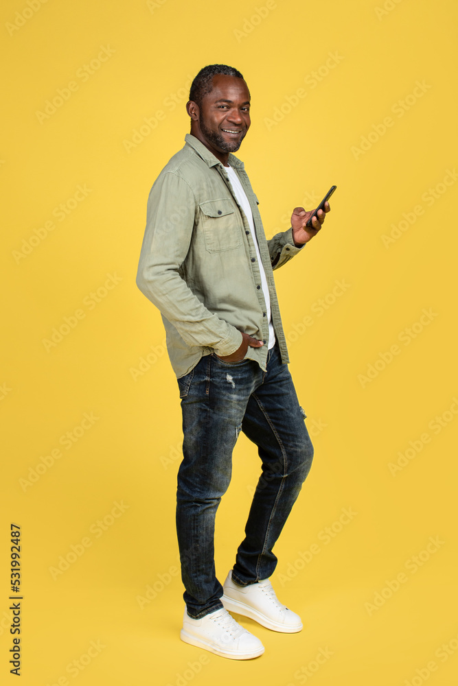 Smiling confident adult african american man in casual typing on phone, chatting in social media Smiling confident adult african american man in casual typing on phone, chatting in social media