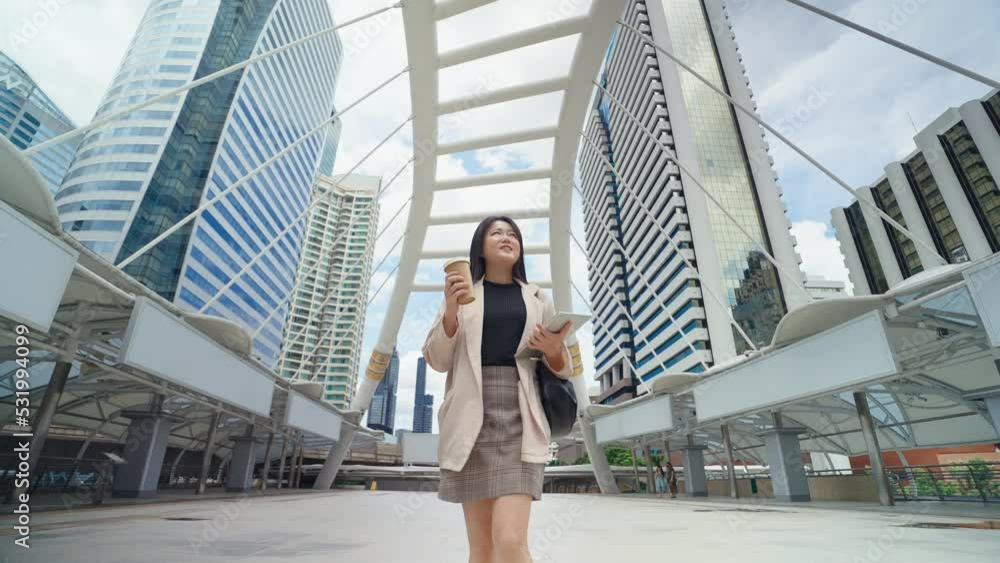 Asian business women going to work in the morning with skyscrapers, She was smiling in her hand holding smartphone and paper cup of coffee. Asian business women going to work in the morning with skyscrapers, She was smiling in her hand holding smartphone and paper cup of coffee.
