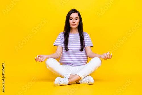 Full size photo of serious pretty lady sit rest relax wear stylish trendy striped outfit white sneakers isolated on yellow background