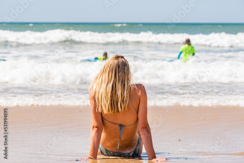 beautiful woman sitting on the beach waiting for her turn to surf.