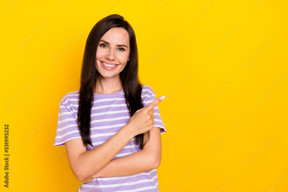 Photo of young attractive woman wear striped purple t-shirt finger directing empty space ad new payment system isolated on yellow color background Photo of young attractive woman wear striped purple t-shirt finger directing empty space ad new payment system isolated on yellow color background