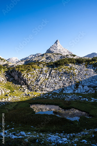 Hidden lake in the mountains with a sharp peak in the background