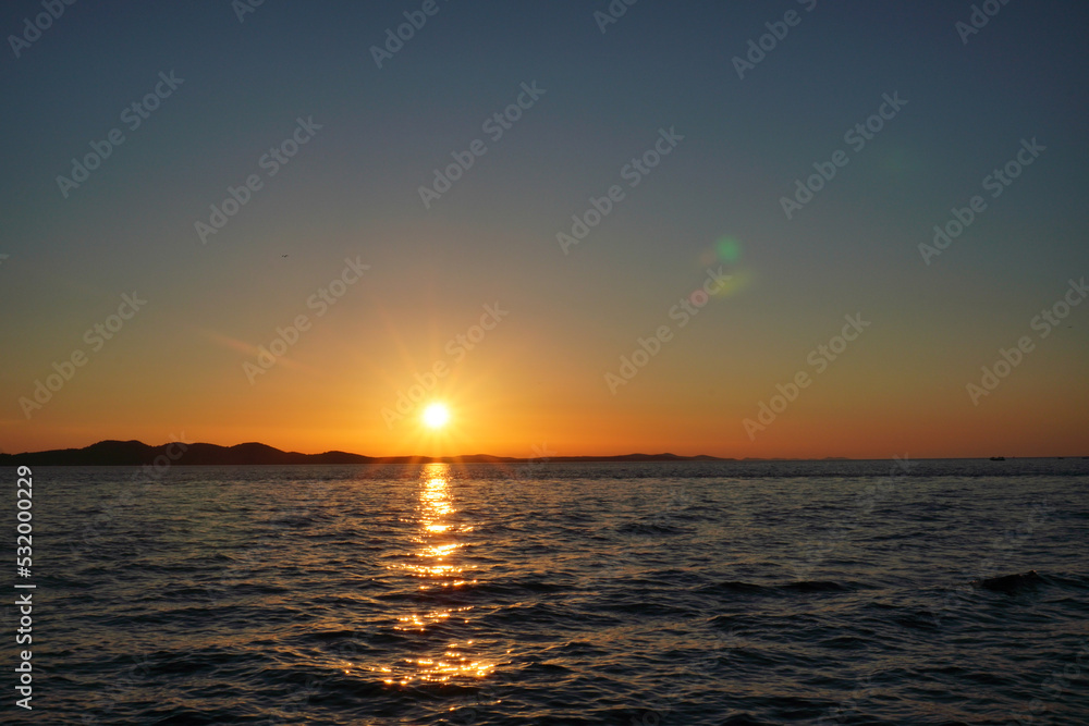 sunset near sea, no clouds. colorful sky and mirroring in water. small waves in ocean. rest on vacation, calm and relax