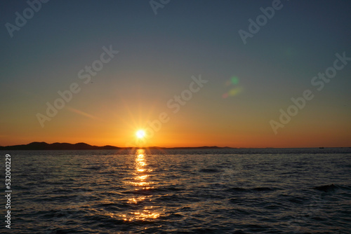 sunset near sea, no clouds. colorful sky and mirroring in water. small waves in ocean. rest on vacation, calm and relax