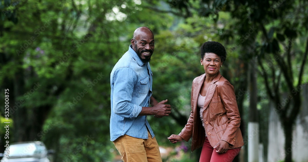 Fototapeta premium Happy carefree black couple dancing together outside in street