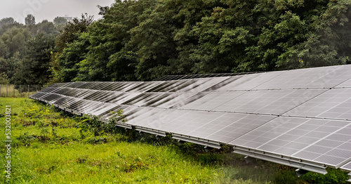 Wielkopowierzchniowe panele solarne w deszczu wśród drzew . Mała elektrownia słoneczna .   photo