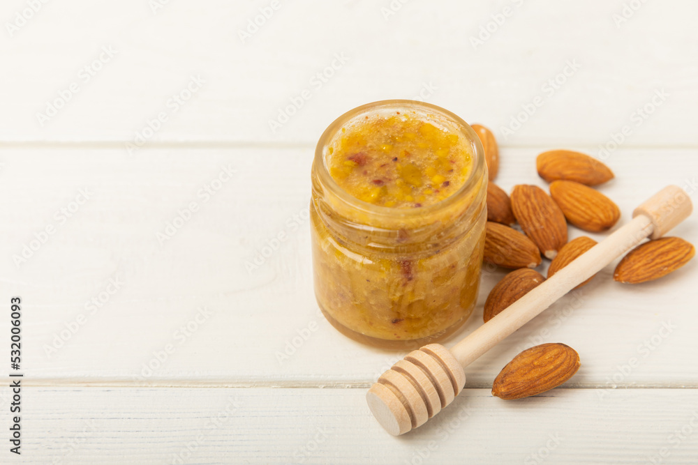 Nut honey jar on white wood. Cold medicine. Useful fortified product with almonds, pistachios, star anise and cinnamon for health and beauty. Vegetarian diet organic product. Copy space.place for text Nut honey jar on white wood. Cold medicine. Useful fortified product with almonds, pistachios, star anise and cinnamon for health and beauty. Vegetarian diet organic product. Copy space.place for text