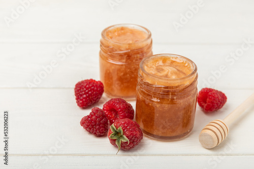 Jar of honey with raspberries on a white wood. Cold medicine. Useful fortified jam for health and beauty. Cream honey. Vegetarian diet organic product. Copy space. place for text