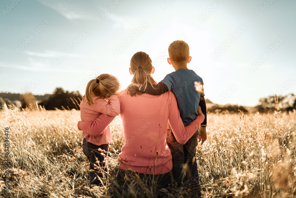 © kieferpix - motherhood, and family parenting concept. mother and children spending time together in nature field looking out to the sunset view.