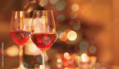 Two glasses of red wine and Christmas lights background. 