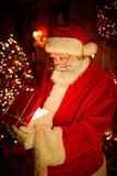 Vertical portrait of traditional Santa Claus opening gift box with magic light and looking surprised