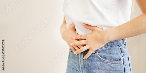 Woman suffering from stomach ache. Holding belly and feeling abdominal menstrual pain or bowel and digestion problems	 photo