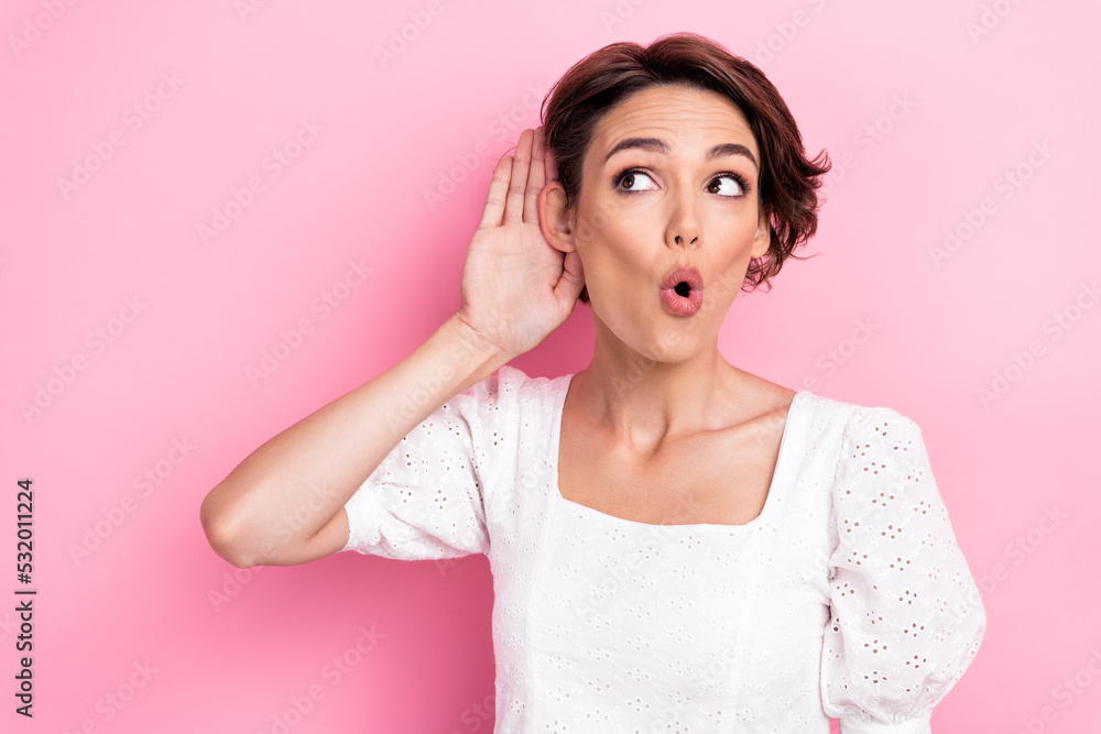 Photo of nice cute gorgeous girl wear white blouse hold hand near ear pouted lips looking at empty space isolated on pink color background Photo of nice cute gorgeous girl wear white blouse hold hand near ear pouted lips looking at empty space isolated on pink color background