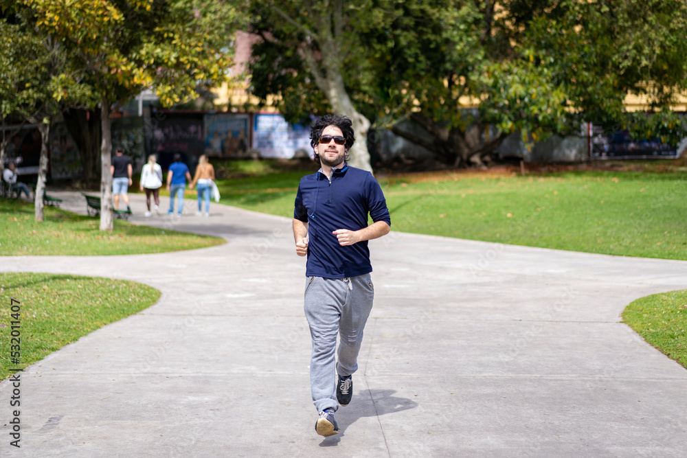 Portrait of handsome attractive mature bearded athletic latin man guy 40s in casual blue t-shirt running at a park