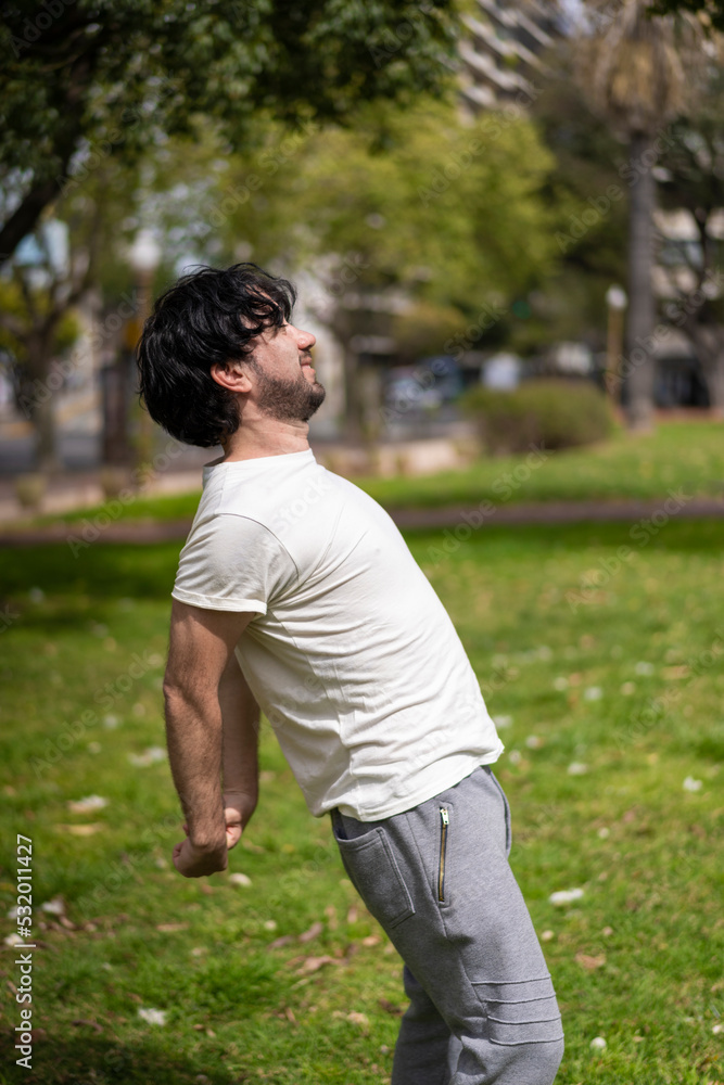 Portrait of handsome attractive mature bearded athletic latin man guy 40s doing stretching exercise, preparing for morning workout in the park.