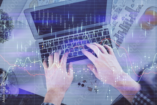 Double exposure of man's hands typing over laptop keyboard and forex chart hologram drawing. Top view. Financial markets concept.