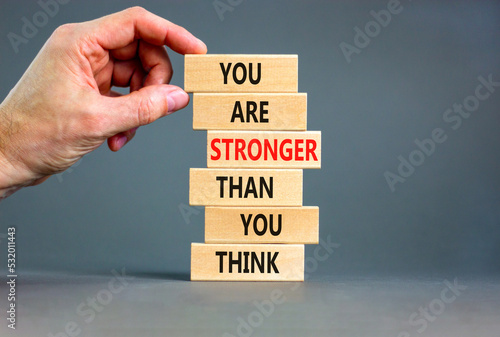Support and be stronger symbol. Concept words You are stronger than you think stronger on wooden blocks. Bussinesman hand. Beautiful grey background. Business and be stronger concept. Copy space.