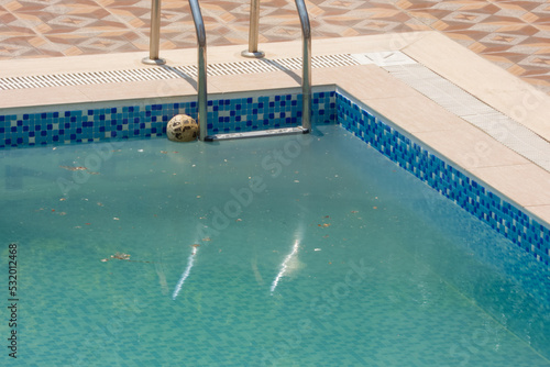 Foto An old ball floats in a pool of dirty water on a sunny day