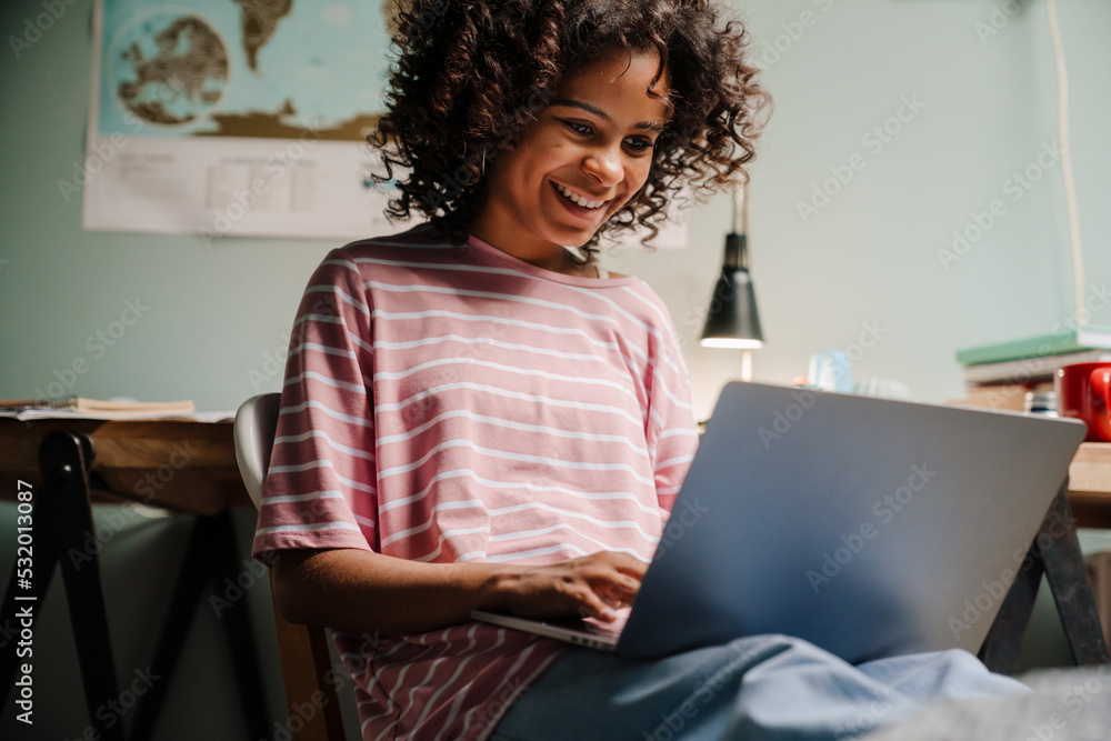 Black girl using laptop and using laptop while sitting on chair Black girl using laptop and using laptop while sitting on chair