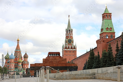 Red square in Moscow with Kremlin tower, Lenin mausoleum and St. Basil's Cathedral background of blue sky with clouds. Symbol of Russian authorities