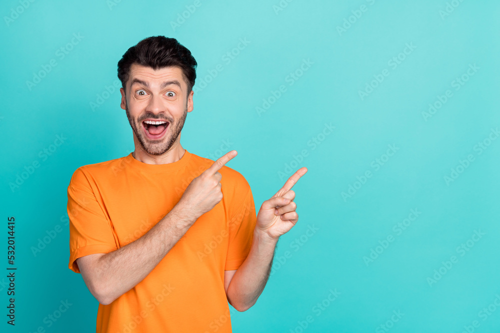 Photo of young handsome funny amazed positive man student wear orange t-shirt fingers pointing empty space excited isolated on aquamarine color background Photo of young handsome funny amazed positive man student wear orange t-shirt fingers pointing empty space excited isolated on aquamarine color background