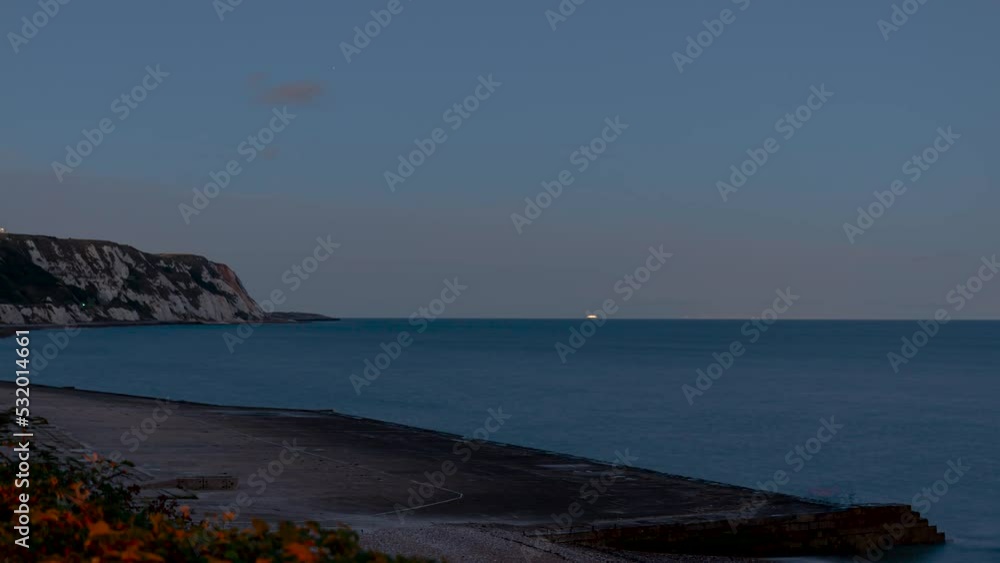 Time lapse shot of the cliffs at Weams Bay at dusk with colorful clouds and the wide ocean Time lapse shot of the cliffs at Weams Bay at dusk with colorful clouds and the wide ocean