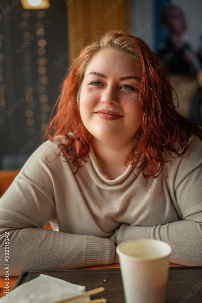 Close-up portrait of a young beautiful red-haired plump girl in a cafe. Close-up portrait of a young beautiful red-haired plump girl in a cafe.