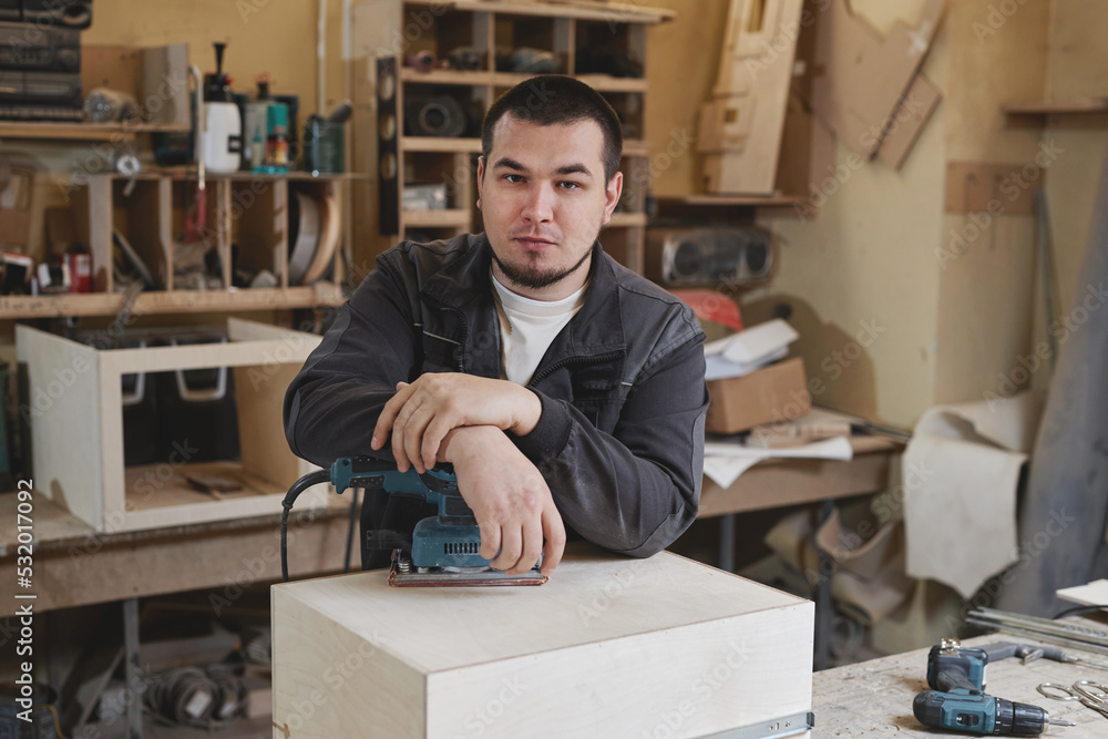 Fototapeta premium Portrait of confident male worker looking at camera while standing in woodworking workshop, copy space