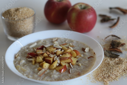 Broken wheat or Dalia porridge. Porridge for breakfast made with broken wheat and milk, served with cinnamon flavored caramalised apples and sliced almonds