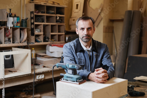 Portrait of senior male worker looking at camera while standing in factory workshop, copy space