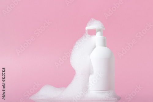 Cosmetics for face, body and hair care. Moisturizer, shampoo or facial cleanser on pink background with foam