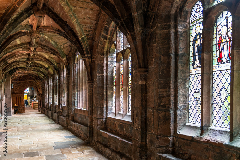 view of the cloister hallway in the courtyard of the historic Chester Cathedral with stained glass windows
