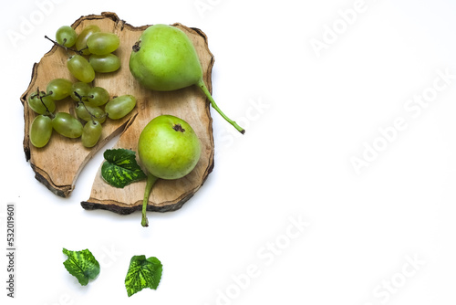 A bunch of grapes and wild pears on a wooden board on a white background. Close-up